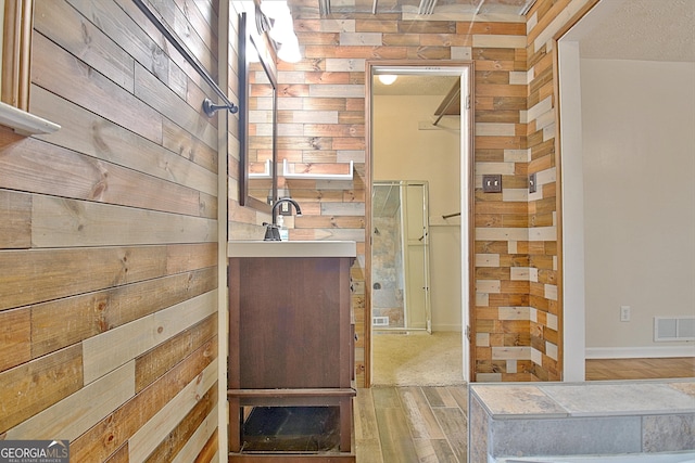 bathroom with wood walls, wood finished floors, and baseboards
