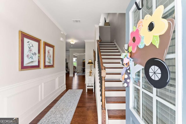 staircase with wood finished floors, a wainscoted wall, and crown molding
