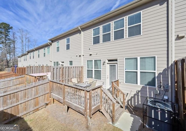 rear view of house with fence and a deck