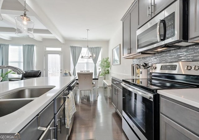 kitchen featuring appliances with stainless steel finishes, a sink, gray cabinets, beam ceiling, and a chandelier