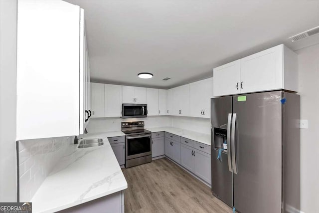 2317 Baywood Dr SE, Atlanta, GA 30315 - kitchen with stainless steel appliances, light stone counters, light wood-style floors, and white cabinets