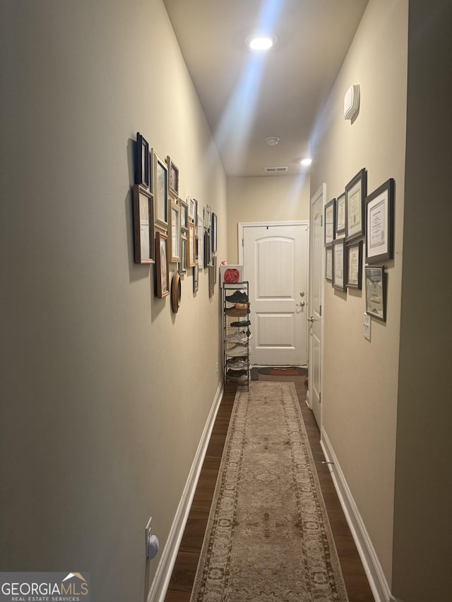 corridor featuring dark wood-style floors and baseboards