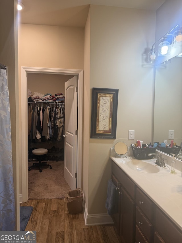 full bath with wood finished floors, vanity, and a walk in closet
