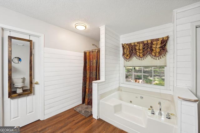 230 Vienna Way, Douglasville, GA 30134 - bathroom with a jetted tub, wood finished floors, a textured ceiling, wooden walls, and toilet