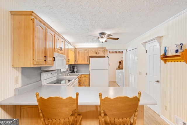 kitchen featuring white appliances, a sink, ceiling fan, a textured ceiling, and wallpapered walls