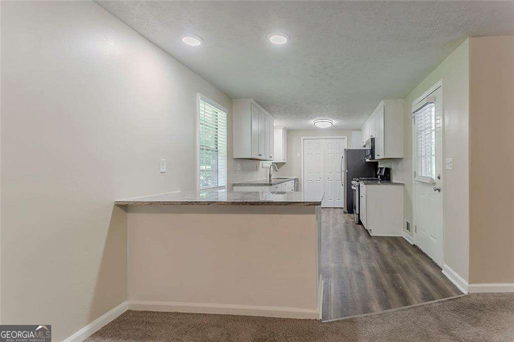 4016 Nations Dr, Douglasville, GA 30135 - kitchen with white cabinets, a textured ceiling, a sink, baseboards, and recessed lighting