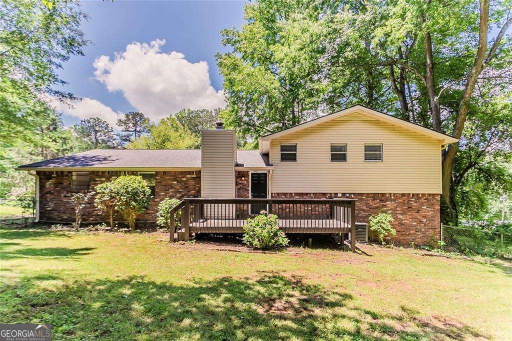 4016 Nations Dr, Douglasville, GA 30135 - rear view of house featuring brick siding, a deck, a yard, and a chimney