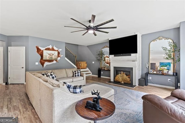 9225 Maple Run Trl, Gainesville, GA 30506 - living room featuring wood finished floors, a ceiling fan, stairs, and a large fireplace