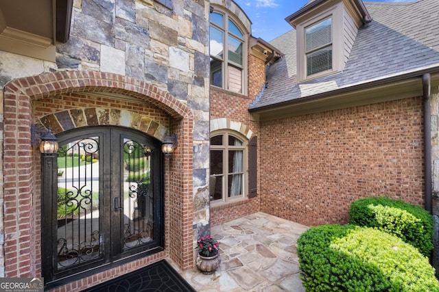 8340 Colonial Pl, Duluth, GA 30097 - view of exterior entry featuring brick siding, roof with shingles, french doors, and stone siding