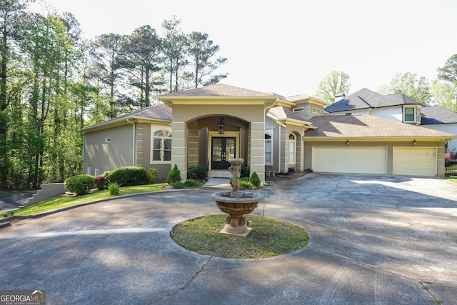 1010 Forest Overlook Dr SW, Atlanta, GA 30331 - mediterranean / spanish house with curved driveway, stucco siding, french doors, a garage, and a shingled roof
