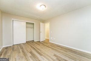 unfurnished bedroom featuring wood finished floors, a closet, and baseboards