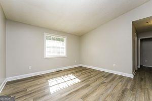 unfurnished room with wood finished floors, vaulted ceiling, and baseboards