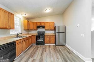 kitchen with freestanding refrigerator, range with gas stovetop, dishwashing machine, a sink, and light countertops