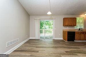 kitchen featuring brown cabinets, baseboards, wood finished floors, a sink, and dishwasher