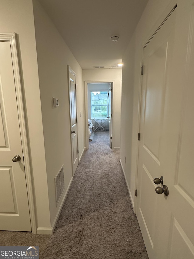 hallway featuring carpet and baseboards
