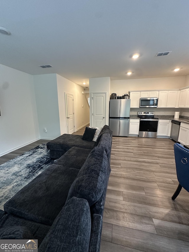 living room featuring wood finished floors, recessed lighting, and baseboards