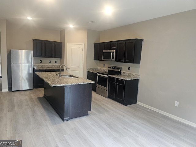 7253 Lacey Dr, Douglasville, GA 30134 - kitchen featuring stainless steel appliances, a sink, light wood-style floors, baseboards, and dark cabinets