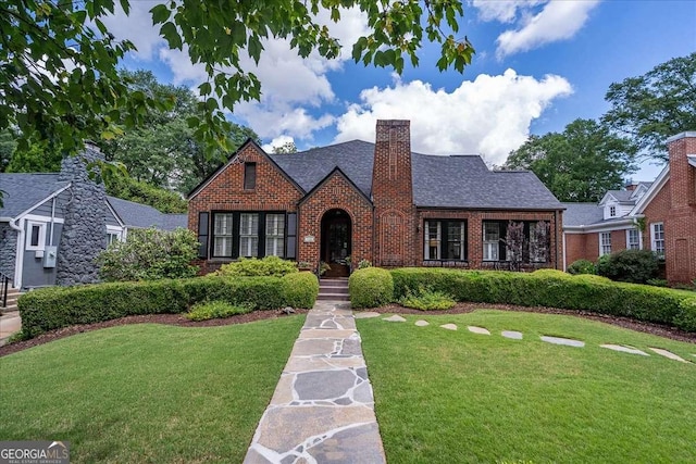 430 Milledge Cir, Athens, GA 30609 - tudor-style house with brick siding, a front yard, a chimney, and roof with shingles