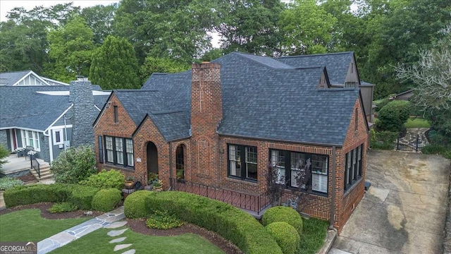 430 Milledge Cir, Athens, GA 30609 - tudor-style house with a shingled roof, concrete driveway, brick siding, and a chimney