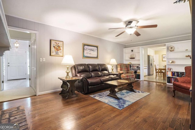 living room featuring ceiling fan, wood finished floors, crown molding, and baseboards