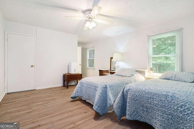 bedroom featuring light wood-style flooring, ceiling fan, and a textured ceiling