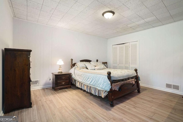 bedroom with light wood-style flooring, a closet, and baseboards