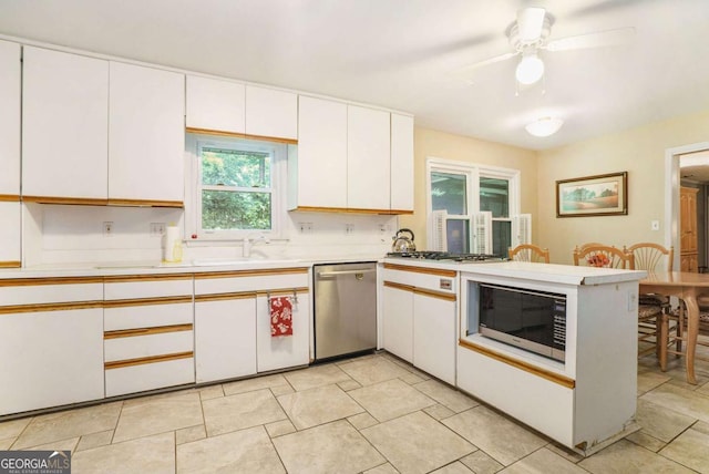 kitchen with appliances with stainless steel finishes, a peninsula, light countertops, white cabinetry, and a ceiling fan