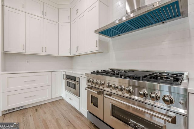 2555 Chattahoochee Ln, Cumming, GA 30041 - kitchen featuring appliances with stainless steel finishes, custom range hood, light countertops, white cabinets, and tasteful backsplash