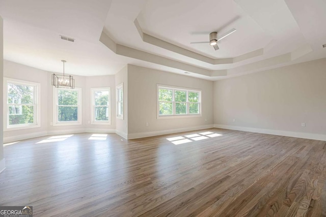 2555 Chattahoochee Ln, Cumming, GA 30041 - unfurnished room featuring a chandelier, a tray ceiling, wood finished floors, and a ceiling fan