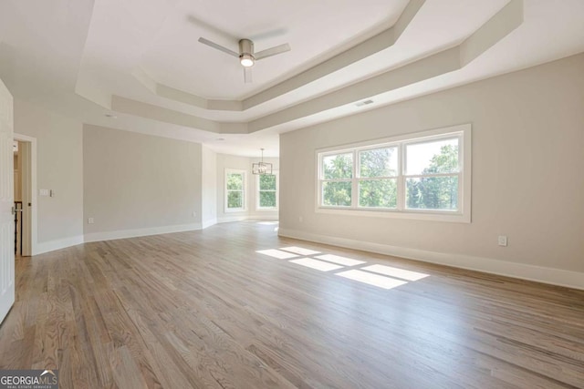 2555 Chattahoochee Ln, Cumming, GA 30041 - empty room with a raised ceiling, light wood-style flooring, and ceiling fan