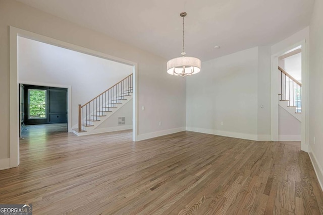 2555 Chattahoochee Ln, Cumming, GA 30041 - spare room featuring stairs, light wood-style flooring, and a chandelier