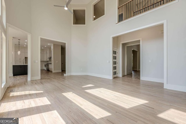 2555 Chattahoochee Ln, Cumming, GA 30041 - unfurnished living room with a towering ceiling, ceiling fan, and light wood finished floors