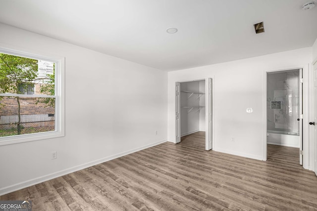 6932 Eunice Dr, Riverdale, GA 30274 - unfurnished bedroom with wood finished floors, baseboards, a spacious closet, ensuite bathroom, and a closet