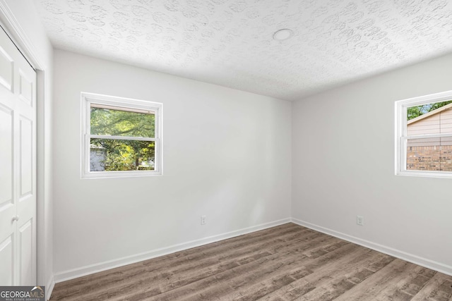 6932 Eunice Dr, Riverdale, GA 30274 - unfurnished bedroom featuring multiple windows, wood finished floors, baseboards, a textured ceiling, and a closet