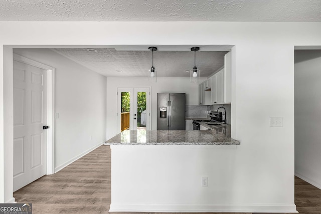 6932 Eunice Dr, Riverdale, GA 30274 - kitchen featuring stainless steel refrigerator with ice dispenser, light stone countertops, french doors, light wood finished floors, and a peninsula