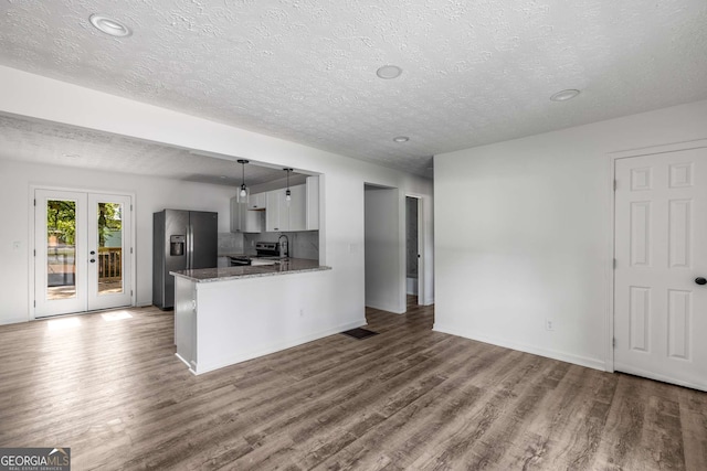 6932 Eunice Dr, Riverdale, GA 30274 - kitchen featuring stainless steel appliances, wood finished floors, a textured ceiling, a peninsula, and dark stone counters