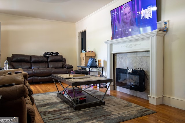 living area featuring ornamental molding, wood finished floors, and a tiled fireplace