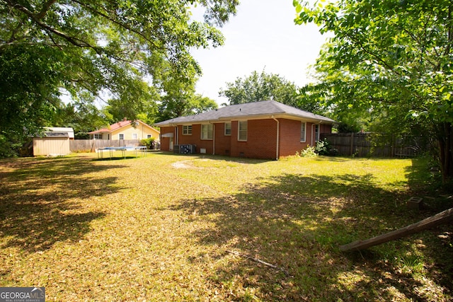 view of yard with a trampoline, a storage unit, and an outbuilding