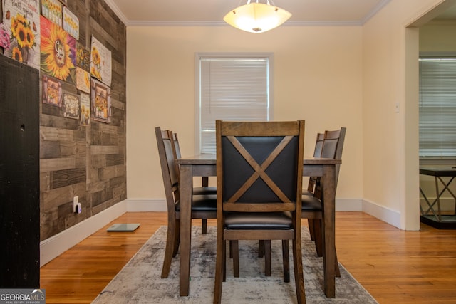 dining room featuring wood finished floors, baseboards, and ornamental molding