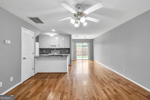2866 Florence Dr, Gainesville, GA 30504 - kitchen with white microwave, a peninsula, light wood-style flooring, ceiling fan, and a textured ceiling