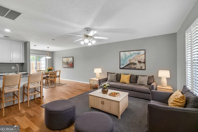 2866 Florence Dr, Gainesville, GA 30504 - living area with light wood-style flooring, a ceiling fan, a textured ceiling, and baseboards