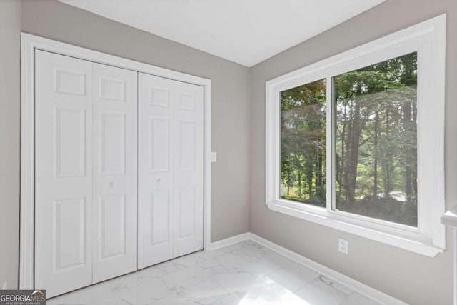 3216 Montheath Ct, Duluth, GA 30096 - unfurnished bedroom with light marble finish floors, baseboards, multiple windows, and a closet