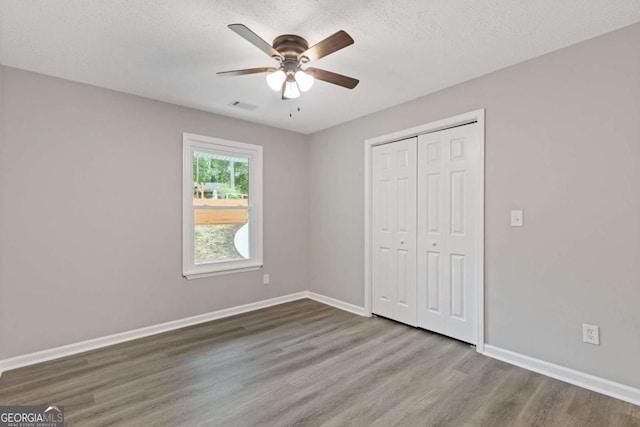3216 Montheath Ct, Duluth, GA 30096 - unfurnished bedroom featuring wood finished floors, a closet, baseboards, a textured ceiling, and ceiling fan