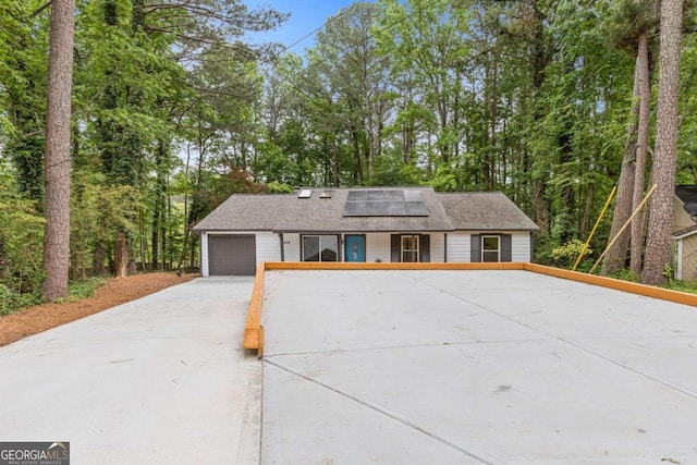 3216 Montheath Ct, Duluth, GA 30096 - view of front of home with roof mounted solar panels, driveway, a garage, and view of wooded area