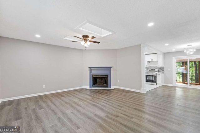 3216 Montheath Ct, Duluth, GA 30096 - unfurnished living room featuring wood finished floors, ceiling fan, a fireplace with flush hearth, baseboards, and recessed lighting