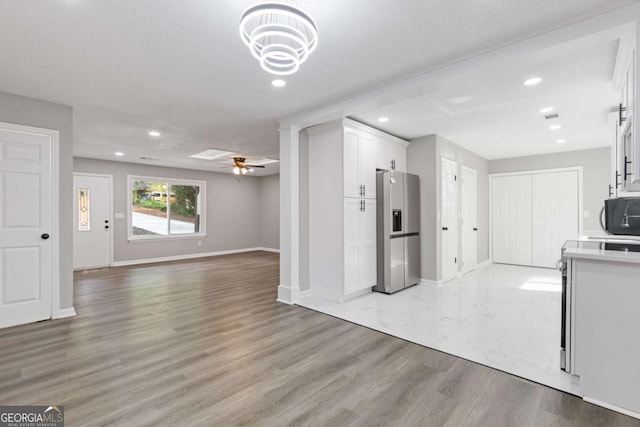 3216 Montheath Ct, Duluth, GA 30096 - kitchen with stainless steel refrigerator with ice dispenser, light countertops, white cabinetry, black microwave, and open floor plan