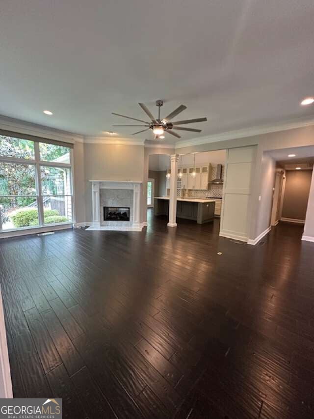1305 Lake Forest Ln, Mcdonough, GA 30253 - unfurnished living room featuring ceiling fan, a glass covered fireplace, baseboards, dark wood-style floors, and crown molding