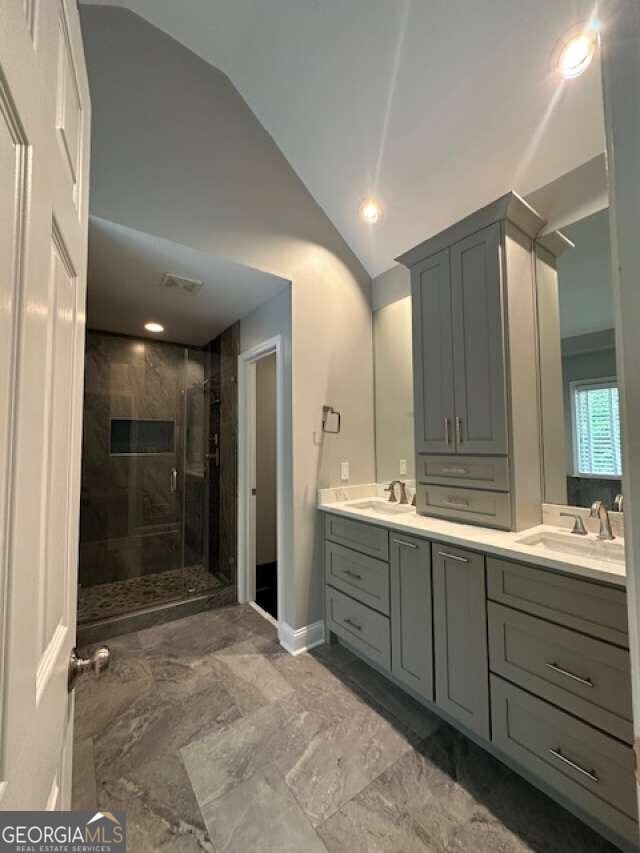 1305 Lake Forest Ln, Mcdonough, GA 30253 - full bath with lofted ceiling, double vanity, a stall shower, and marble look tiles