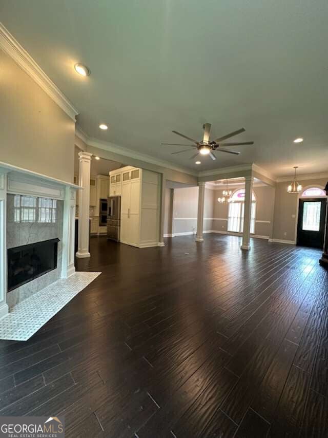 1305 Lake Forest Ln, Mcdonough, GA 30253 - unfurnished living room featuring a chandelier, ornamental molding, a ceiling fan, a high end fireplace, and dark wood finished floors