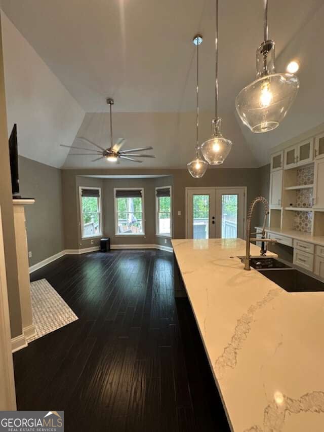 1305 Lake Forest Ln, Mcdonough, GA 30253 - kitchen featuring french doors, lofted ceiling, white cabinetry, dark wood finished floors, and hanging light fixtures